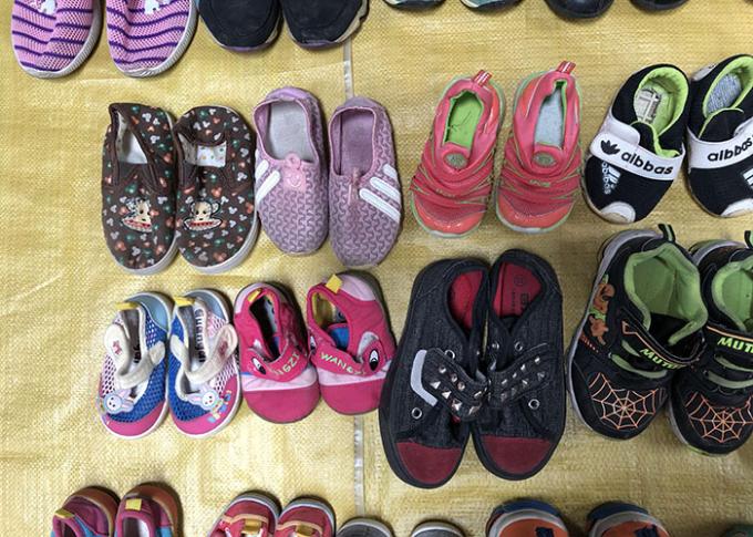 Die Hand der Kinder zweiter kleidet Schuhe/bunte benutzte Sport-Schuhe für Sommer